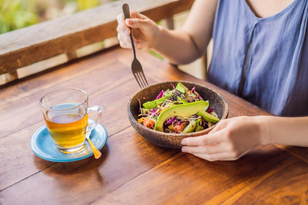 Woman eating healthy salad and drinking green tea