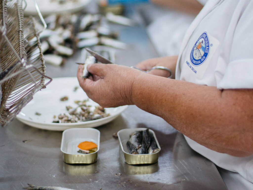 Pinhais cannery worker hand-cutting sardine and putting sardines in tins with spice and veggies