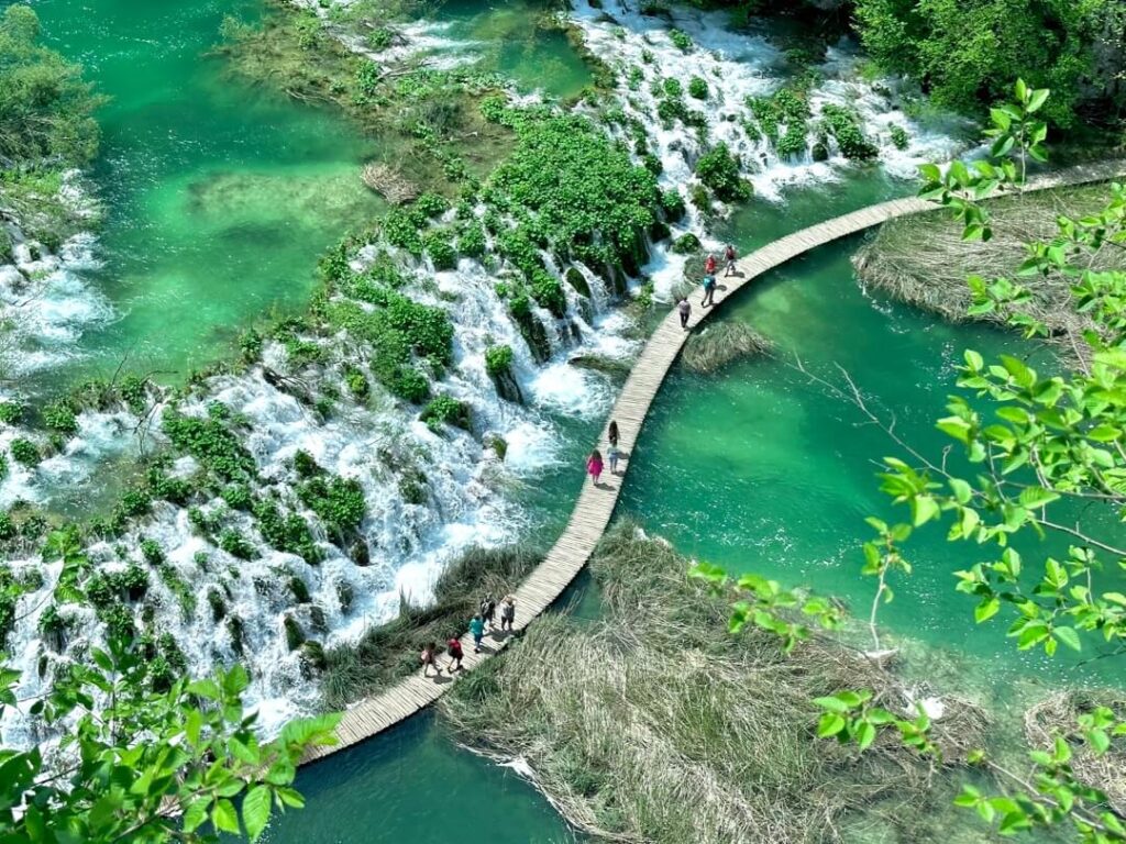 View of the most famous and picturesque part of Lower Lakes, windy boardwalk in the middle of lakes next to low and layered waterfalls, in Plitvice Lakes National Park, Croatia