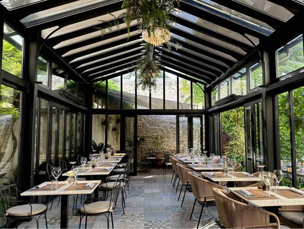 The indoor seating area of Corte Restaurant in Zadar, Croatia, is like an elegant modern glass barn that look out to the secret garden
