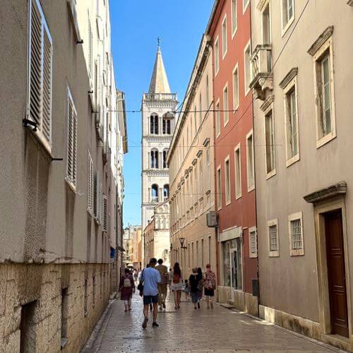 Narrow street with the bell tower in the distance in Zadar, Croatia, showing Zadar architecture