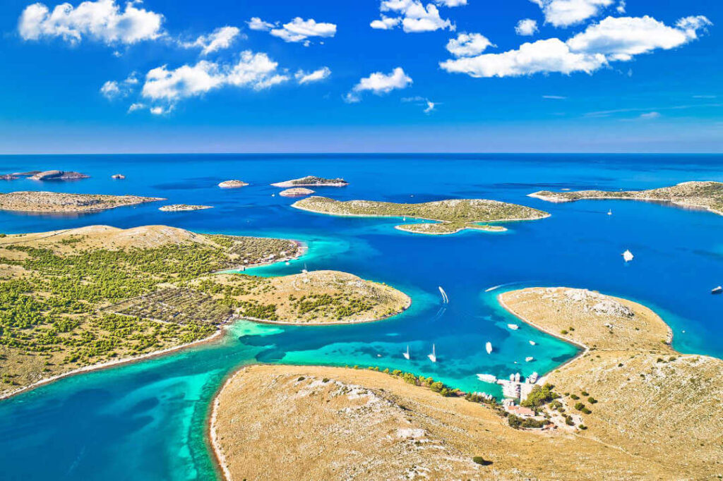 Aerial view of the stunning Kornati National Park archipelago with turquoise and bright blue waters and boats cruising through, in Croatia