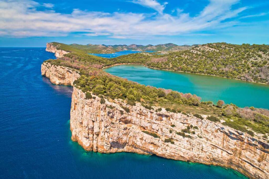 Aerial view of the Telascica Nature Park and the green Mir lake on Dugi Otok, separated from the sea by dramatic cliff drop off in Croatia