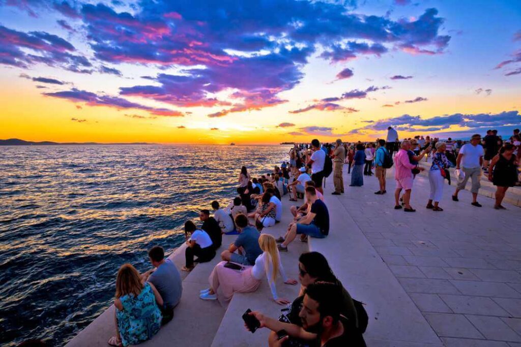 People gather to watch gorgeous sunset at the Sea Organ steps in Zadar, Croatia