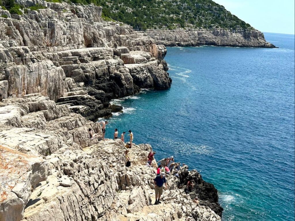 People standing on the cliffs to Odysseus Cave on the Island of Mljet in Croatia